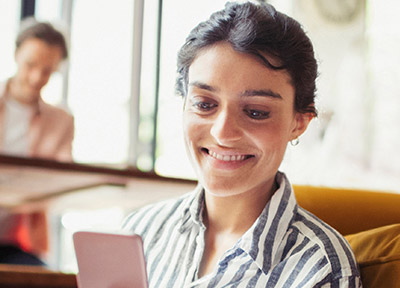 A woman smiles looking at her phone.